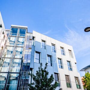 Immeubles à l'architecture moderne avec façade en verre et métal sous un ciel bleu dégagé.